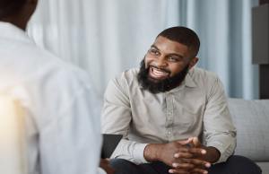 Black man with a bread enjoying his therapy session with a caring counselor