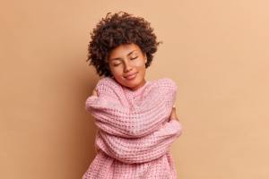 Woman in pink hugging herself