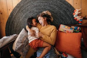 Mom hugging her child on the floor and laughing