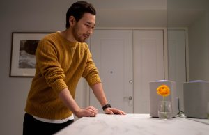 Man in yellow sweater smiling while looking in the mirror