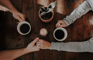 two people holding hands over a wood table