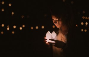 Woman holding lantern looking at it.