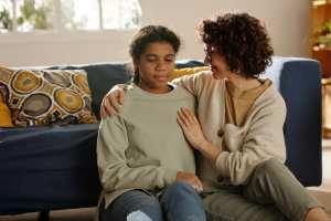 Mother and teen daughter talking in their living room