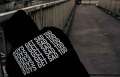 person in black sweatshirt with white writing on a bridge