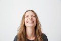 Portrait of young emotional beautiful girl laughing with closed eyes over white background