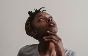 Woman looking up in thought with her hand on her chin.