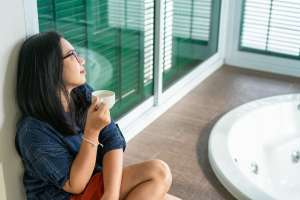 Woman drinking coffee by a bathtub