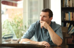 Pensive man in a coffee shop looking through a window