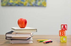 stacked books with red apple and abc blocks