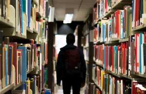 man standing between library books