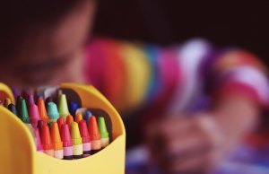 box of crayons and child drawing