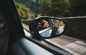 man taking picture in side view mirror