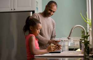 man helping daughter wash hands in kitchen sink