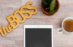 yellow the boss sign with ipad, plant and coffee on wood desk