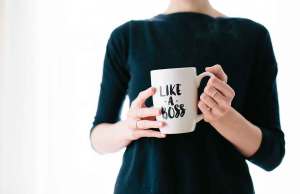 person holding white coffee cup in black sweater