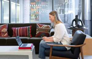 woman in white shirt and jeans sitting looking at computer