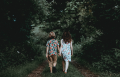 two children holding hands, walking on a path through the woods