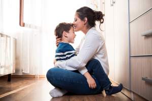 Mother holding her son on her lap and kissing his head