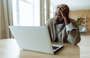 man staring at laptop with hand on head