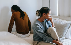 displeased woman with partner sitting on bed