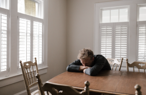 man-in-gray-long-sleeve-shirt-sitting-on-brown-wooden-chair