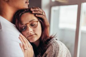 Man hugging woman and cradling her head