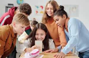 Young children huddle around a smartphone