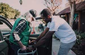 Volunteer-helps-elderly-man-with-walker