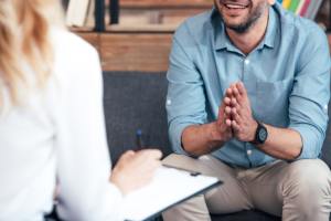 Female therapist with a clipboard talking with older male client