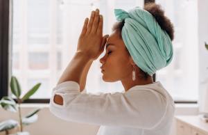 Woman meditates and reads energy with eyes closed in green turban