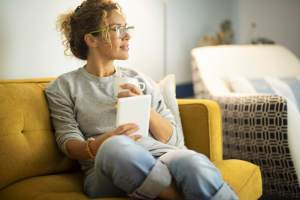 Woman on a couch reading and drinking coffee