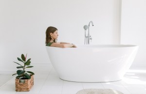 Woman sits in bathtub fully clothed.