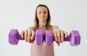 purple-dumbbells-in-hands-of-positive-sportswoman