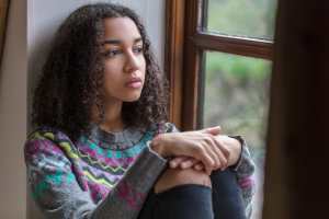Girl in a gray sweater sitting by a window