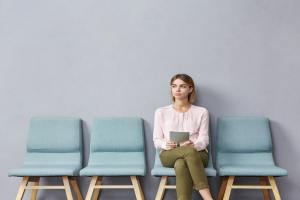 Woman sitting with tablet in a waiting room with her legs crossed.