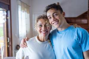 Teenager standing with their mother in the kitchen