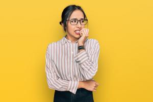 Woman with glasses biting her nails anxiously