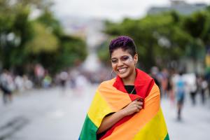 Queer individual wearing a Pride flag