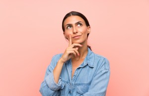 oung woman over isolated pink background thinking an idea