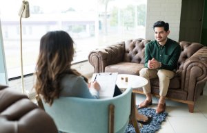 Businessman listening to female counselor during therapy session while sitting in office