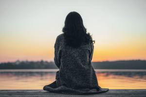 Woman sitting at a lake at sunset