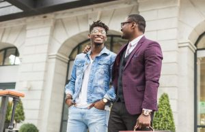 Two young and stylish African American men in the city smiling and talking. father and adult son relationship