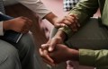 Young African American female psychologist keeping hand of wrist of male patient sitting in front of her and sharing his problems