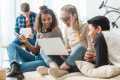 Three teenagers sitting on a couch looking at a laptop